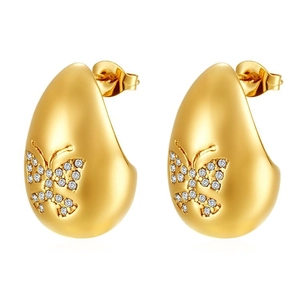 Gros plan de boucles d'oreilles goutte dorées avec zircon papillon sur fond blanc