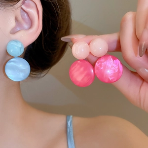 Close-up of resin hoop earrings with blue marble and pink textured swirl patterns