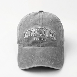 Detailed view of white New York embroidery on a grey washed denim baseball cap texture