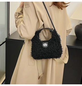 Detail of a plush black shoulder bag with silver twist lock on a beige trench coat