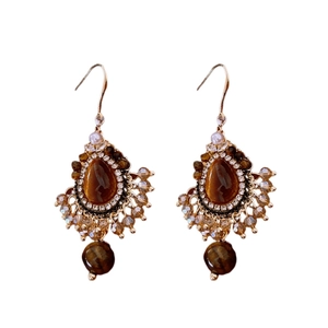Boucles d'oreilles vintage en or avec oeil de tigre brun et perles sur fond blanc