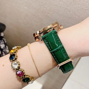 Detail of green crocodile leather strap and rose gold watch case on female wrist