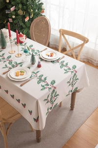 Detailed texture of beige cotton linen tablecloth with festive red berries and green leaves