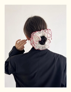 Détail d'un chouchou géant en organza avec bordure rouge ondulée sur queue
