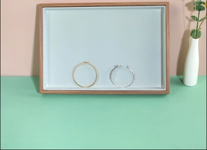 Rosewood grain jewelry display tray featuring gold and silver bangles on two-tone background