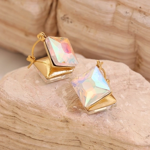Geometric gold stud earrings with iridescent aurora crystals on natural stone background