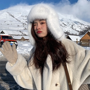 Detail showing plush white faux fur winter trapper hat with ear flaps in snowy mountains