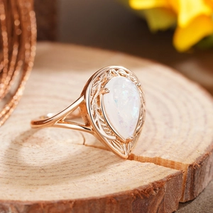 Makroaufnahme: Roségoldener Tropfenring mit birnenförmigem Opal und Blattgravur-Details