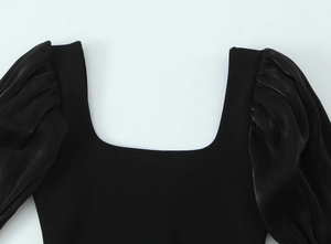 Détail du col carré et des manches bouffantes plissées sur un haut noir élastique femme