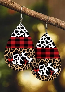 Detailed view of teardrop leather earrings with cow, plaid, and leopard prints hanging on a branch