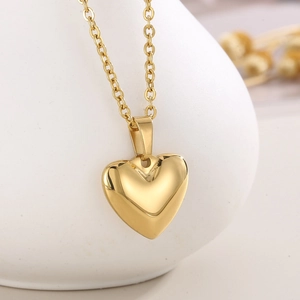 Gros plan d'un collier à pendentif cœur doré sur un élégant vase en céramique blanche