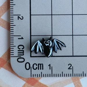 Close-up of a 1.5cm black resin bat bead on a scale mat for DIY crafts decoration