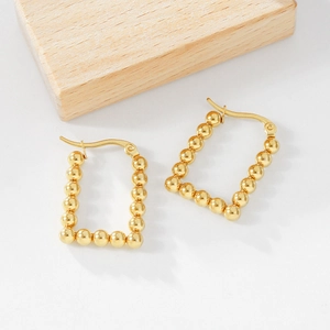 Detail view of gold-plated geometric beaded rectangular earrings with secure hoop closure