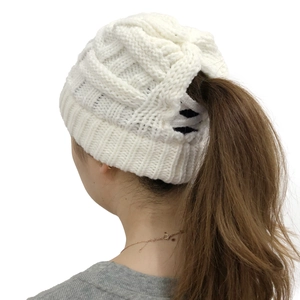 Close-up of white cable-knit ponytail beanie with a functional top opening for hair