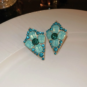Detailed view of geometric earrings with blue crystals on white ceramic background