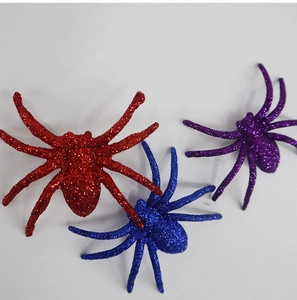 Glittery decorative plastic spiders in red, blue, and purple for Halloween decor
