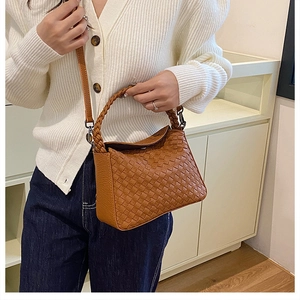 Close-up of woven cognac handbag texture and metallic hardware with a shoulder strap