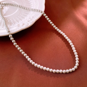 Close-up of elegant cream pearl necklace resting on vintage white embossed porcelain plate