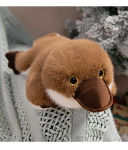 Close-up of soft brown platypus plush toy with golden glitter eyes on a blue blanket