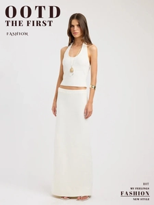 Full body view of white knitted two-piece set featuring halter top and maxi skirt