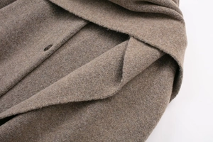 Macro shot of brown wool coat lapel and button showing premium knit texture