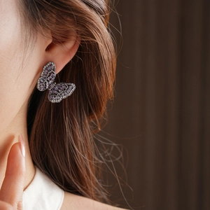Macro shot of butterfly stud earring featuring purple marquise gemstones on a vintage silver base