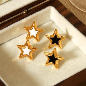 Detail of four gold star earrings with white and black enamel in a velvet jewelry box