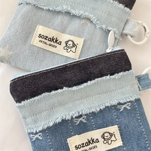 Detailed view of patchwork denim wallet featuring frayed edges and a white zipper closure