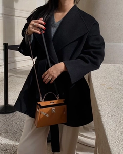 Detailed close-up of a brown leather handbag with a metal buckle lock and black shoulder strap