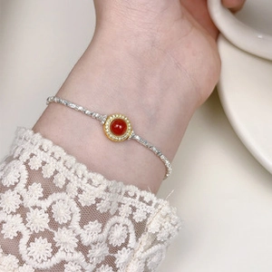Detail of s925 silver bracelet with red gemstone and sparkling accents on wrist