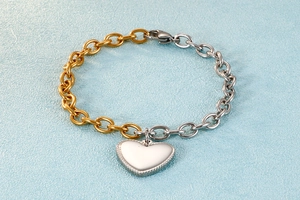 Close-up of two-tone stainless steel chain bracelet with a textured heart charm