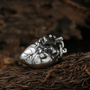 Vintage anatomical silver heart pendant necklace on dark wood texture background