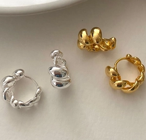 Close-up of gold and silver twisted hoop earrings with S925 hallmark detail