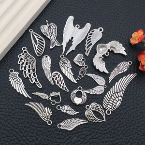 Collection of silver vintage alloy wing and winged heart pendants on black background