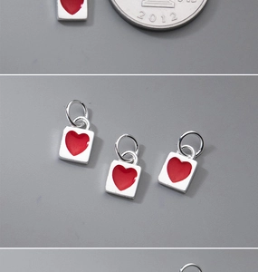 Dettaglio macro di ciondoli quadrati in argento con smalto a cuore rosso e anello