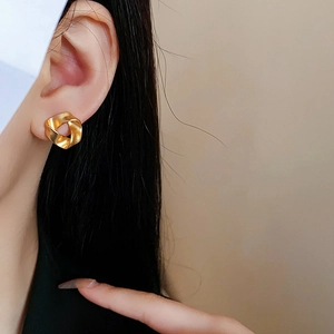 Detailed side view of a model wearing a matte gold twisted geometric earring for women