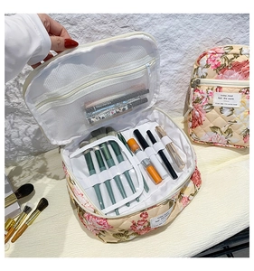 Detail of floral quilted makeup bag interior featuring elastic brush loops and mesh pocket