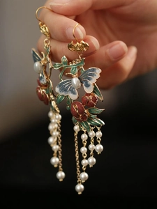 Détail des boucles d'oreilles papillon vintage avec fleurs en émail et pompons