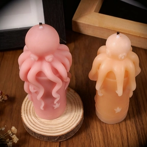 Artistic octopus candles in pink and orange colors on a warm wooden tabletop