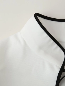 Dettaglio dell'elegante collo alto con finiture nere a contrasto sull'abito bianco