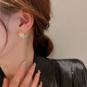 Detailed side view of model wearing gold circular earrings with white zircon accents