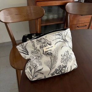 Detail of floral jacquard cosmetic bag with 'simple wish' tag on a wooden table
