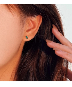 Close-up of a silver rectangular emerald zircon stud earring worn by a model
