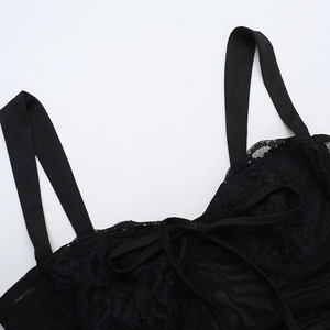 Dettaglio di un top in pizzo nero con ricami floreali e un piccolo fiocco centrale
