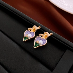 Vue macro de boucles d'oreilles nœud vintage en or avec cœur émaillé violet et perle