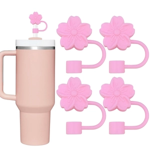 Pink cherry blossom silicone straw covers shown set on a tumbler with extra floral caps