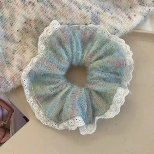 Close-up of rainbow knit scrunchie with white lace trim on a minimalist background
