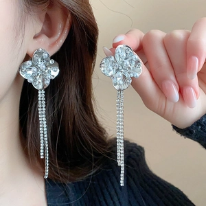 Close-up of long silver tassel earrings with flower studs and delicate white pearls