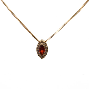 Golden necklace with a teardrop red zircon pendant surrounded by small clear gemstones