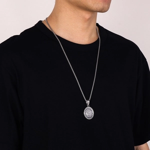 Close-up of a silver hammered texture circular pendant necklace worn by a male model